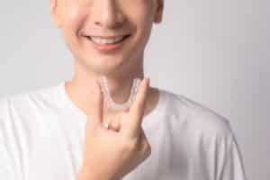 Young man holding his set of Invisaligners about to put them in his mouth.