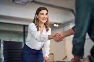 A corporate woman with invisible orthodontics shaking someone's hand