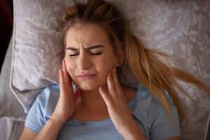 A woman with TMJ holding her jaw