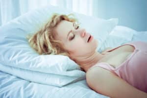 A woman with sleep apnea lying on her back and snoring