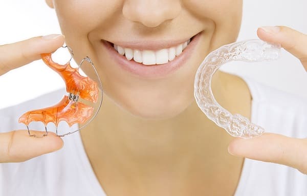 hands holding retainer for teeth and tooth tray 1766076318 Retainers woman smiling 1 Retainers in Denver, CO