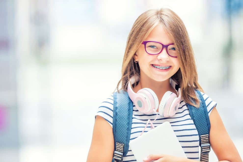 Child smiling with braces, representing common signs a child may need orthodontic treatment.