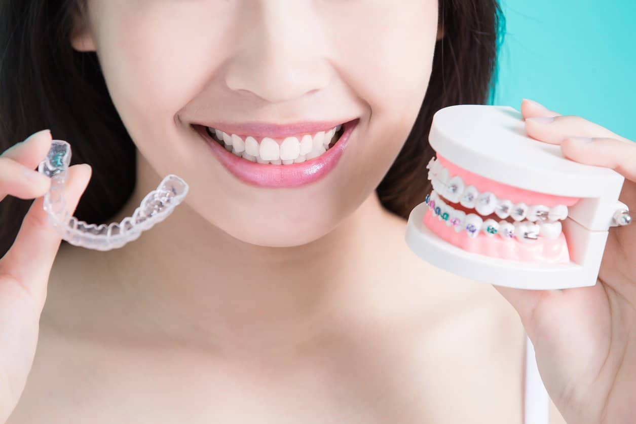 Person comparing clear aligners and braces, representing orthodontic options for teens.