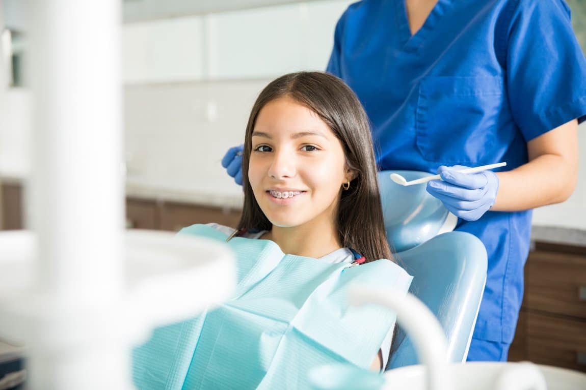 Teen with braces smiling during an orthodontic visit, representing what to expect during the first few days with braces.